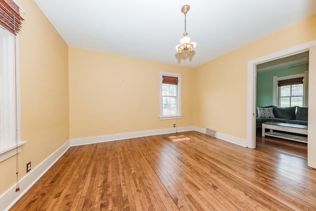 12220 W Highland Rd, Mequon, WI 53097 - unfurnished room with light wood-style flooring, a chandelier, and baseboards