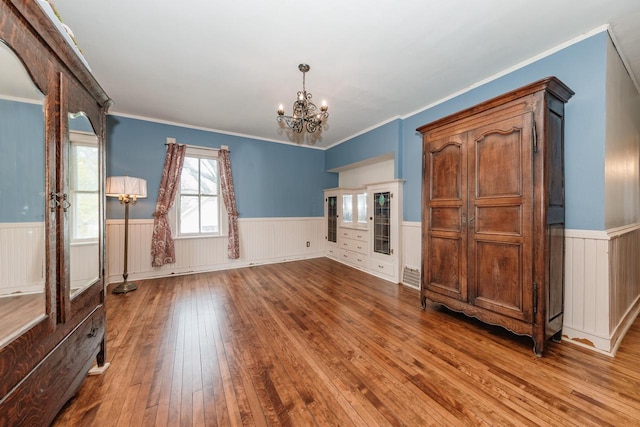 12220 W Highland Rd, Mequon, WI 53097 - unfurnished living room with wainscoting, a chandelier, hardwood / wood-style floors, and crown molding