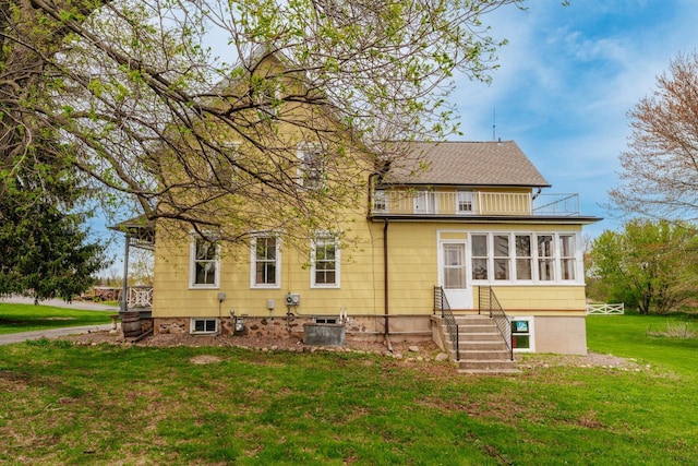 12220 W Highland Rd, Mequon, WI 53097 - rear view of property with a balcony, a yard, entry steps, central air condition unit, and roof with shingles