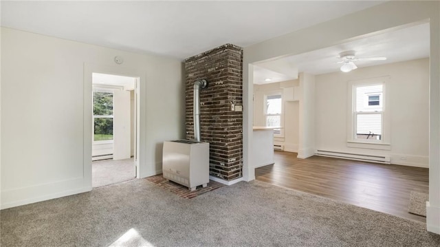carpeted spare room with a baseboard heating unit, a ceiling fan, and baseboards