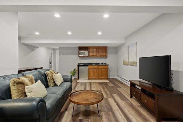 956 Kingston Cir, Sun Prairie, WI 53590 - living area featuring wood finished floors, bar with sink, recessed lighting, baseboards, and a baseboard heating unit