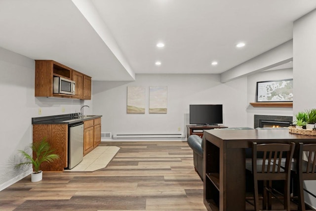 956 Kingston Cir, Sun Prairie, WI 53590 - kitchen with stainless steel appliances, open shelves, baseboard heating, a lit fireplace, and light wood-style flooring