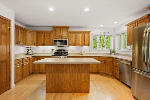 956 Kingston Cir, Sun Prairie, WI 53590 - kitchen with stainless steel appliances, a center island, light countertops, light wood-style floors, and brown cabinetry
