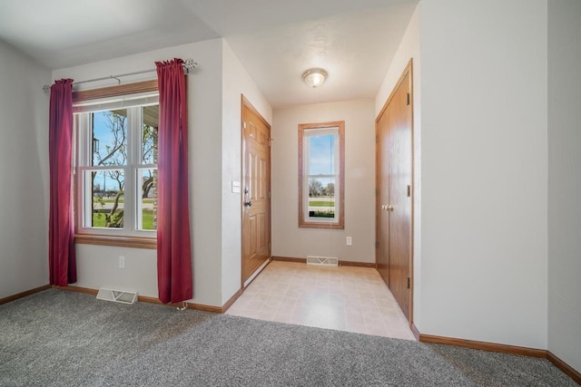 doorway featuring baseboards and light carpet
