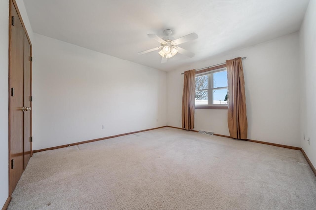 unfurnished room with light colored carpet, baseboards, and ceiling fan