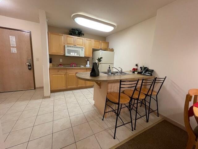 123 Center St Unit 101, Lake Geneva, WI 53147 - kitchen with white appliances, light brown cabinetry, a breakfast bar area, a peninsula, and light tile patterned floors