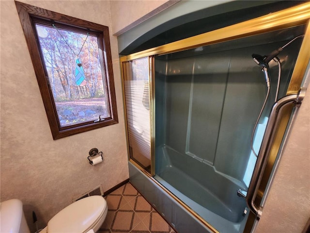 1451 90th Ave, Amery, WI 54001 - bathroom featuring toilet, bath / shower combo with glass door, a textured wall, and tile patterned flooring