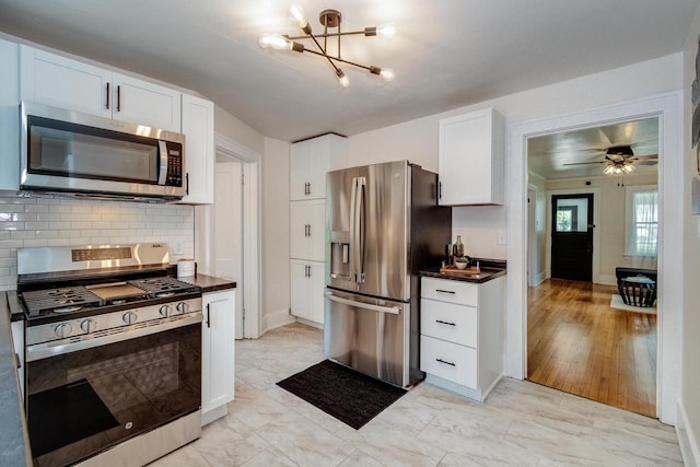 932 Washburn St, Beloit, WI 53511 - kitchen with appliances with stainless steel finishes, dark countertops, tasteful backsplash, white cabinetry, and a chandelier
