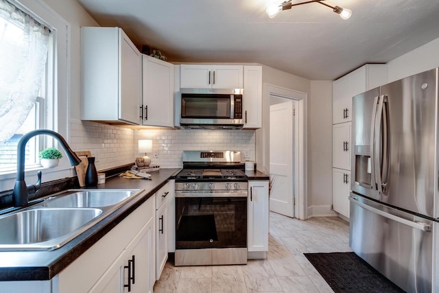 932 Washburn St, Beloit, WI 53511 - kitchen with stainless steel appliances, a sink, dark countertops, light marble finish flooring, and tasteful backsplash