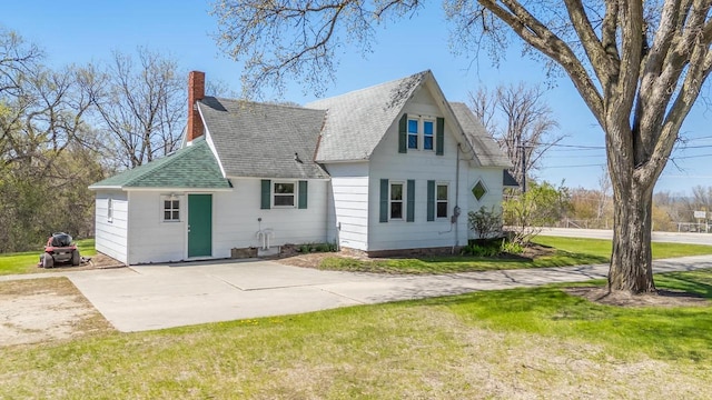 2780 Humboldt Rd, Green Bay, WI 54311 - rear view of house with a chimney, roof with shingles, a lawn, and concrete driveway