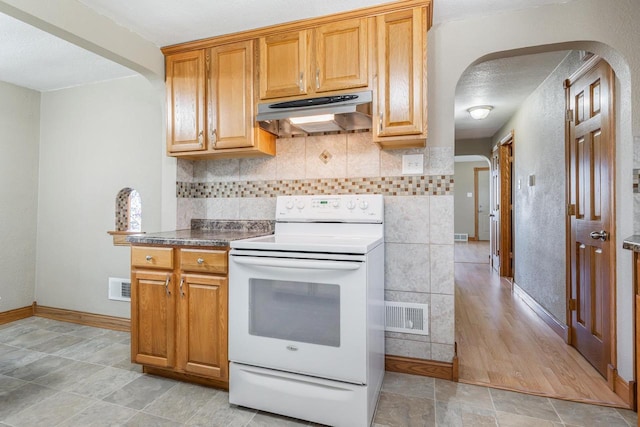 2780 Humboldt Rd, Green Bay, WI 54311 - kitchen featuring white electric range, arched walkways, under cabinet range hood, and baseboards