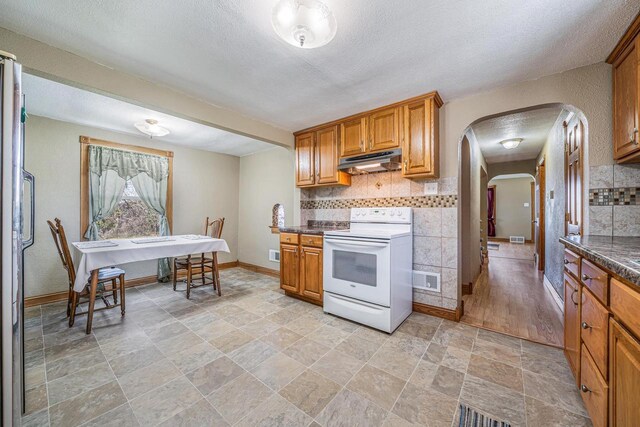 2780 Humboldt Rd, Green Bay, WI 54311 - kitchen featuring electric stove, arched walkways, under cabinet range hood, tasteful backsplash, and dark countertops