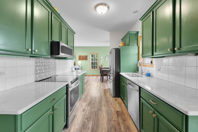 575 Fargo Trl, Middleton, WI 53562 - kitchen featuring stainless steel appliances, green cabinetry, wood finished floors, a sink, and tasteful backsplash