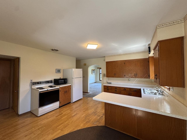 201 Broadway St, Rollingstone, MN 55969 - kitchen featuring white appliances, a sink, arched walkways, light countertops, and brown cabinets