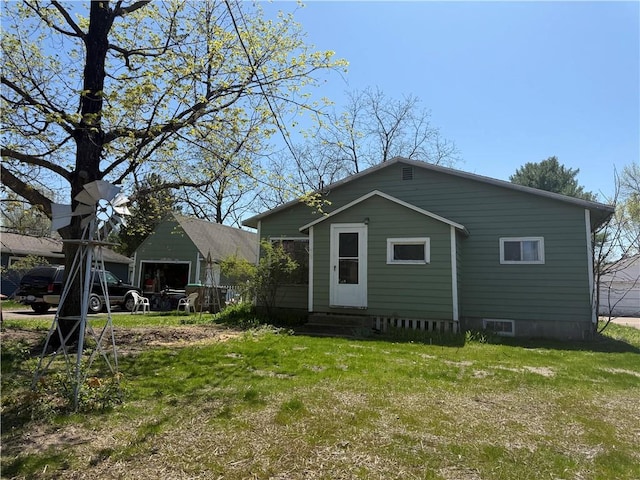 back of property with entry steps and a lawn