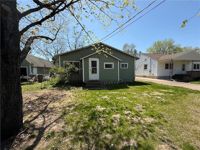 rear view of property featuring entry steps and a lawn