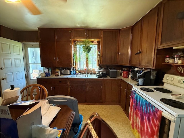 kitchen featuring white electric range oven, light countertops, and a sink