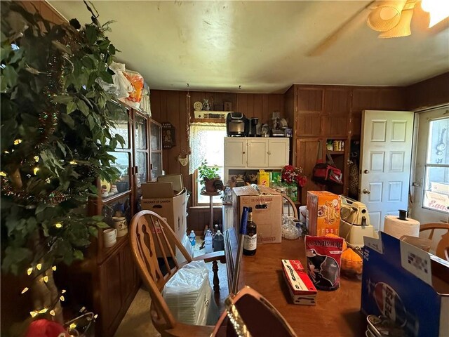 dining room with ceiling fan and wood walls