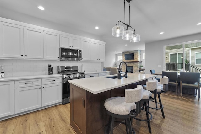 2149 Rosenberg Ln, Sun Prairie, WI 53590 - kitchen featuring appliances with stainless steel finishes, tasteful backsplash, a stone fireplace, recessed lighting, and white cabinetry