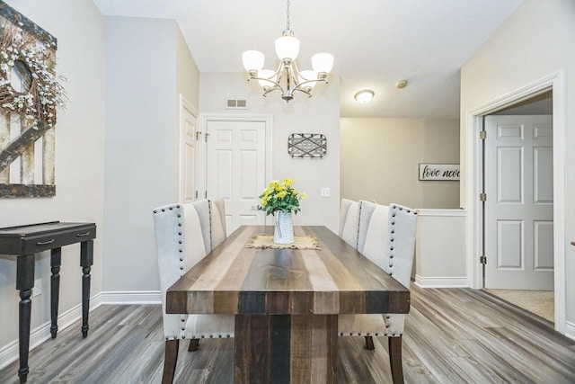 dining room featuring a chandelier, wood finished floors, and baseboards