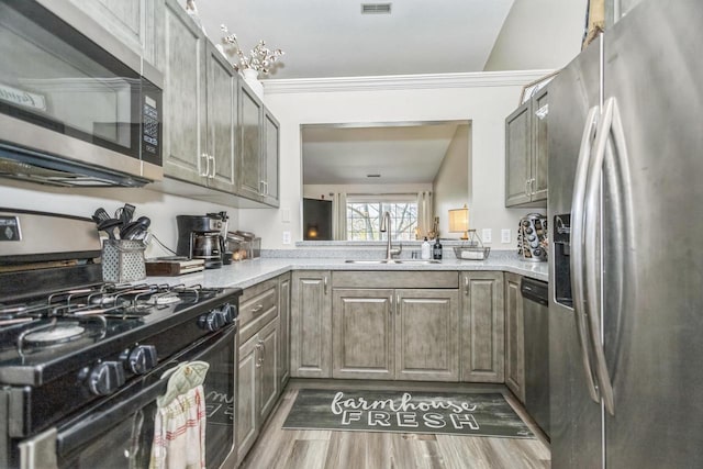 kitchen with stainless steel appliances, a sink, wood finished floors, and light stone countertops