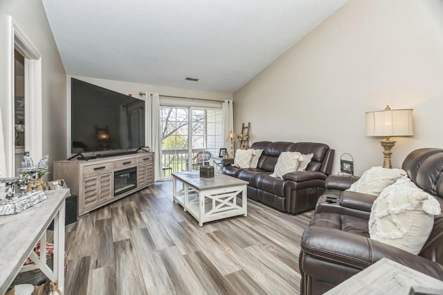 living area with vaulted ceiling and wood finished floors