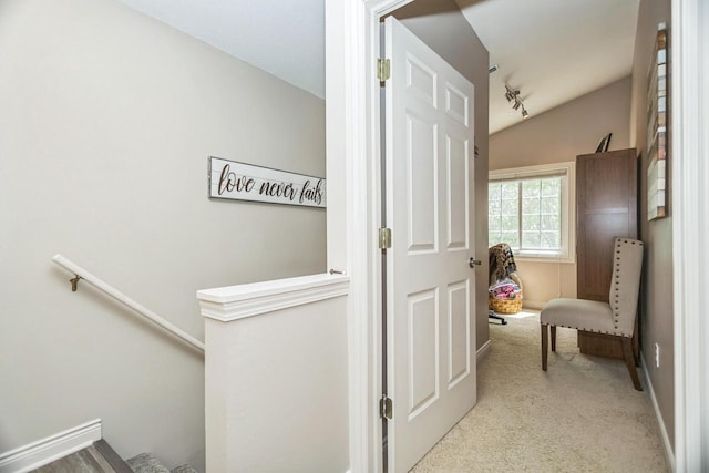 hallway with carpet flooring, an upstairs landing, vaulted ceiling, and baseboards