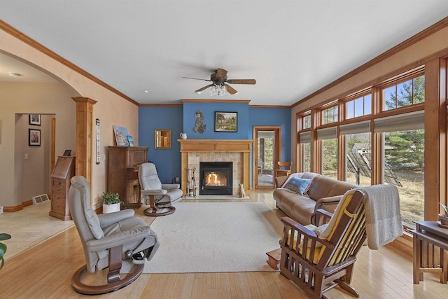 1229 Riverwood Ln, Sobieski, WI 02413 - living area with arched walkways, a ceiling fan, wood-type flooring, a tiled fireplace, and crown molding