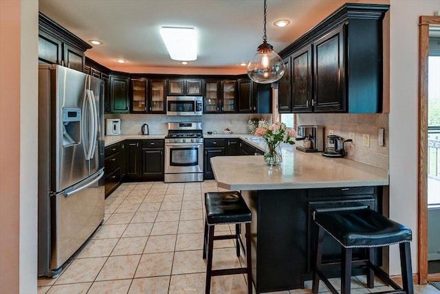 717 Larvik Ln, Stoughton, WI 53589 - kitchen with appliances with stainless steel finishes, a peninsula, light countertops, tasteful backsplash, and light tile patterned floors