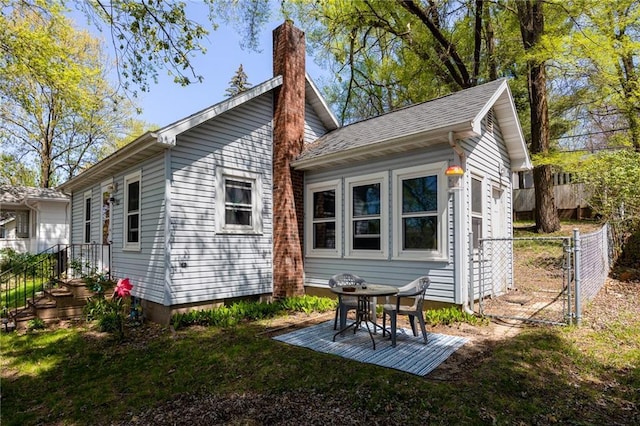 rear view of property featuring a chimney and fence