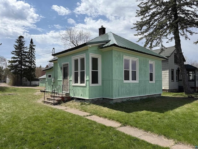 613 Vaughn Ave, Ashland, WI 54806 - view of home's exterior featuring a chimney, a lawn, metal roof, and entry steps