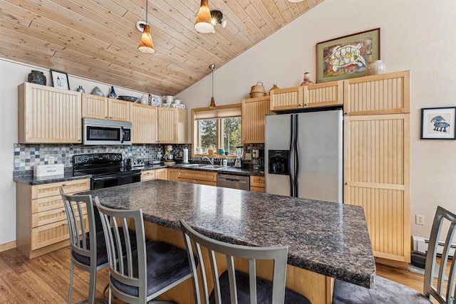 87985 Bark Point Rd, Herbster, WI 54844 - kitchen featuring stainless steel appliances, vaulted ceiling, dark countertops, backsplash, and light wood-style flooring