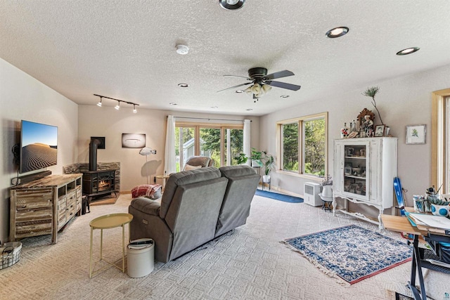 87985 Bark Point Rd, Herbster, WI 54844 - living area with a wood stove, ceiling fan, plenty of natural light, a textured ceiling, and baseboards