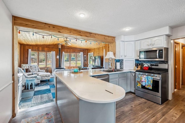 111 Rolphs Point Dr, Shell Lake, WI 54871 - kitchen featuring appliances with stainless steel finishes, open floor plan, a peninsula, wooden walls, and white cabinets