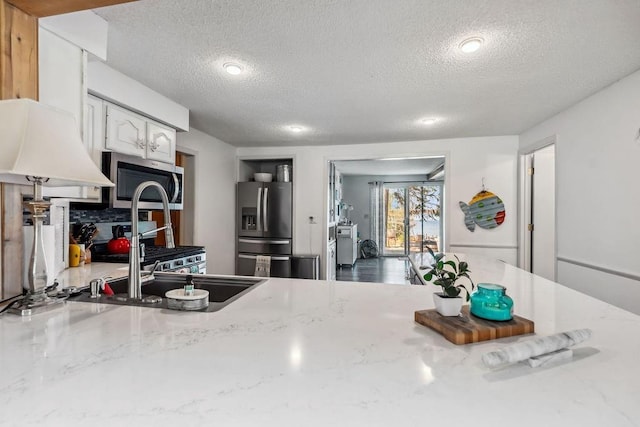 111 Rolphs Point Dr, Shell Lake, WI 54871 - kitchen featuring stainless steel appliances, a textured ceiling, light stone counters, a sink, and white cabinetry