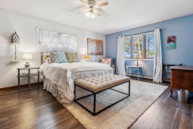 111 Rolphs Point Dr, Shell Lake, WI 54871 - bedroom featuring baseboard heating, dark wood-type flooring, a textured ceiling, baseboards, and a ceiling fan