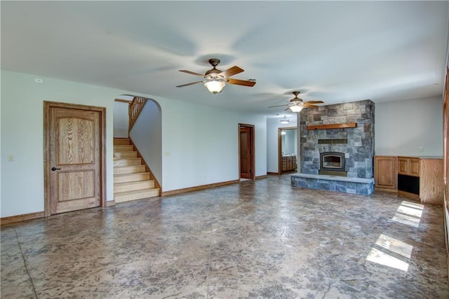 4221 Lassek Ct, Eau Claire, WI 54703 - unfurnished living room featuring a stone fireplace, stairway, a ceiling fan, and baseboards