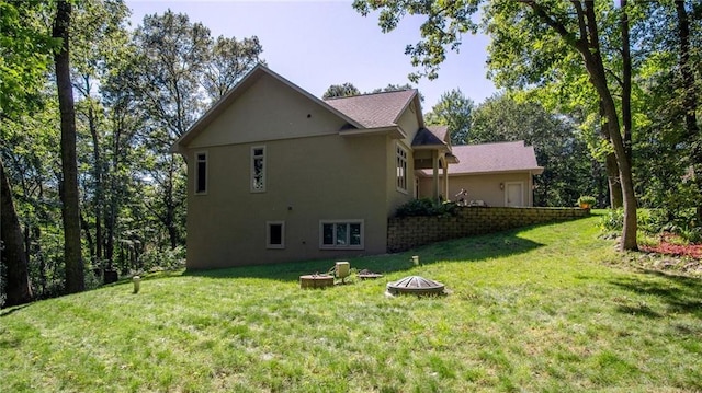 4221 Lassek Ct, Eau Claire, WI 54703 - view of home's exterior featuring a fire pit, a lawn, and stucco siding