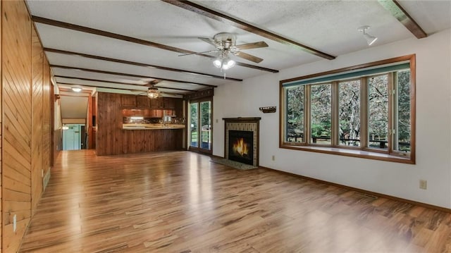 9027 W County Road D, Holcombe, WI 54745 - unfurnished living room featuring beamed ceiling, light wood finished floors, ceiling fan, a fireplace, and a textured ceiling