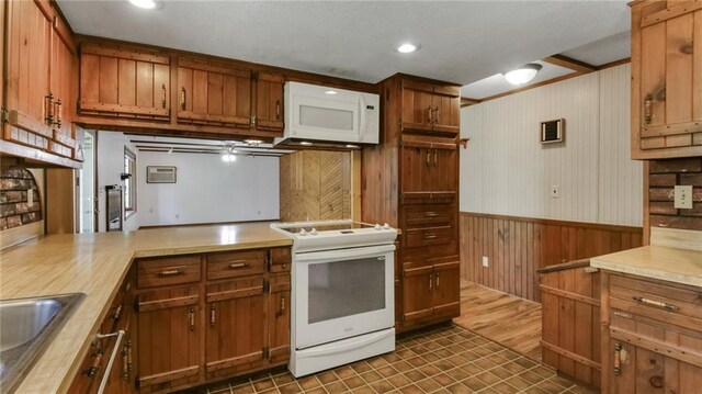 9027 W County Road D, Holcombe, WI 54745 - kitchen featuring white appliances, wooden walls, wainscoting, brown cabinetry, and light countertops