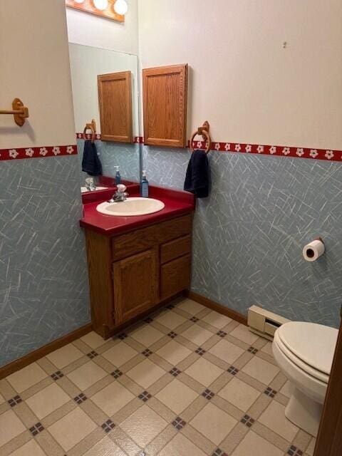 bathroom with a baseboard radiator, wainscoting, vanity, and toilet