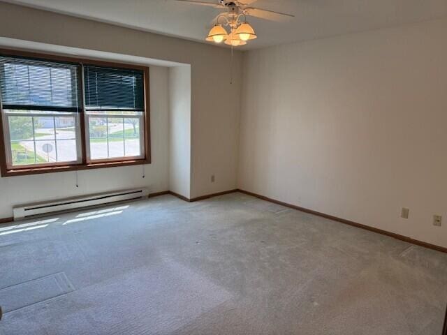 unfurnished room with a baseboard radiator, light carpet, ceiling fan, and baseboards