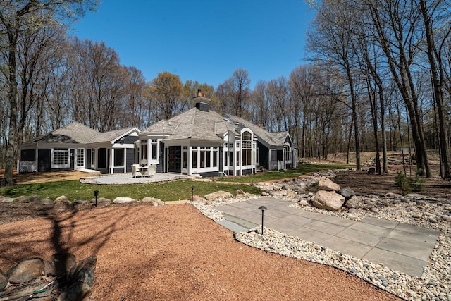 889 Horns Corners Rd, Cedarburg, WI 53012 - back of house with a sunroom, a chimney, a patio, a lawn, and a shingled roof