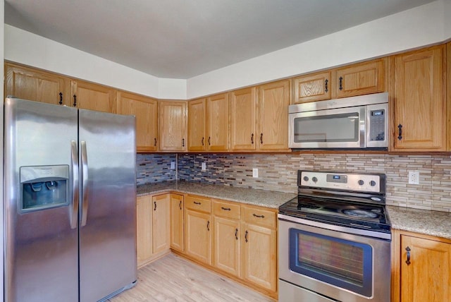 821 Ondossagon Way, Madison, WI 53719 - kitchen featuring stainless steel appliances, light stone counters, light wood-type flooring, and tasteful backsplash