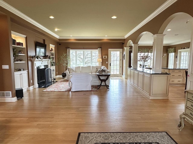 N3684 Petrie Rd, Lake Geneva, WI 53147 - living area with ornate columns, arched walkways, light wood-style flooring, crown molding, and a fireplace with flush hearth