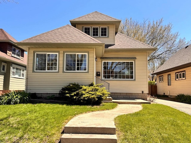 bungalow-style home featuring a front lawn and a shingled roof