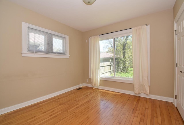 spare room with baseboards and light wood-style floors