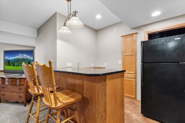 2583 Countryside Ln, Richfield, WI 53076 - kitchen with freestanding refrigerator, a kitchen breakfast bar, decorative light fixtures, dark stone counters, and a peninsula
