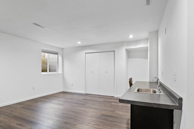 interior space featuring a sink, dark countertops, dark wood-style floors, recessed lighting, and baseboards