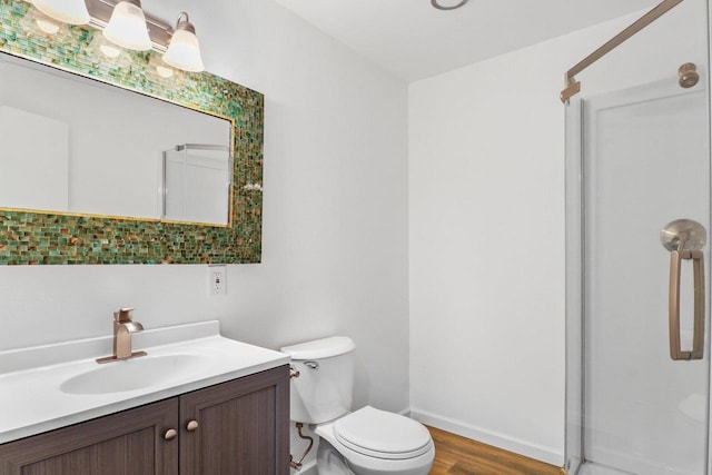 bathroom with toilet, vanity, baseboards, wood finished floors, and a shower with shower door